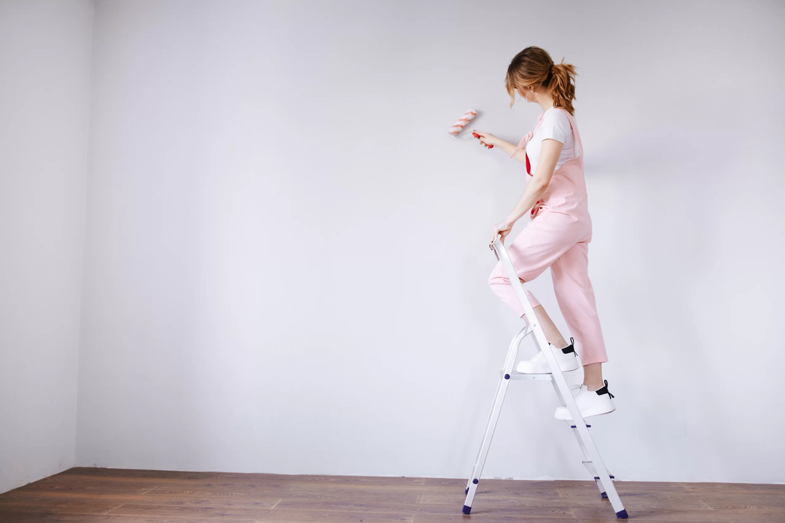 A woman in a pink jumpsuit is painting a wall reno r3s2j35 scaled. Jpg