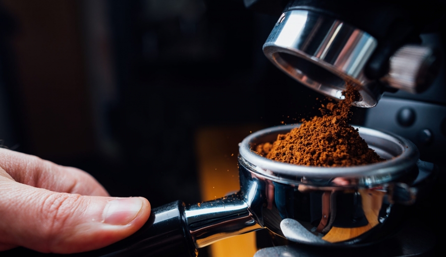 ground coffee pouring into a portafilter with a grinder, closeup